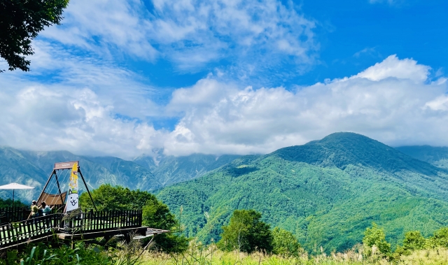 【推奨写真】白馬岩岳meadowの緑のグラデーションと白馬三山— 夏の晴れた日、ソファシートで寛ぐ人々